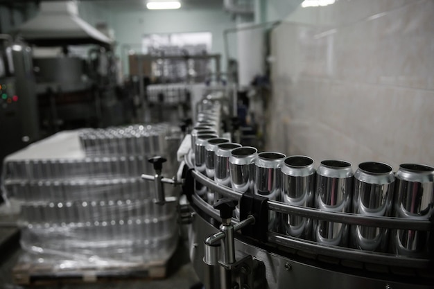 Technologische lijn voor het bottelen van bier in brouwerij Lege aluminium bierblikjes bewegen langs de transportband Schone bierflessen bewegen langs de transportbandIndustriële productielijn