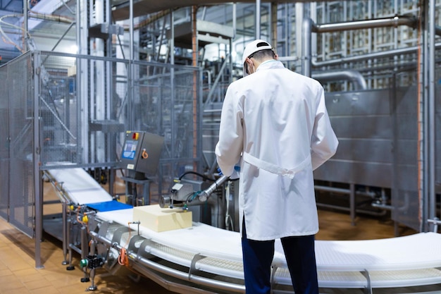 Foto il tecnologo prepara la linea di produzione stando in piedi vicino allo schermo digitale nel dipartimento del caseificio