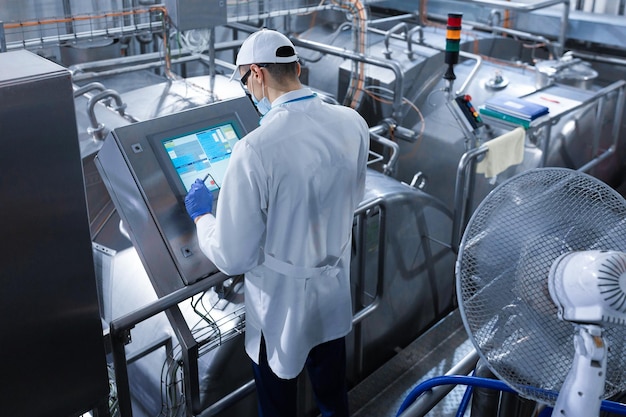 Technologist make set up of the production line while standing near digital screen at the department of dairy factory