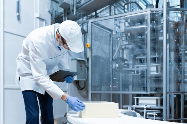 Foto il tecnologo prepara la linea di produzione stando in piedi vicino allo schermo digitale nel dipartimento del caseificio