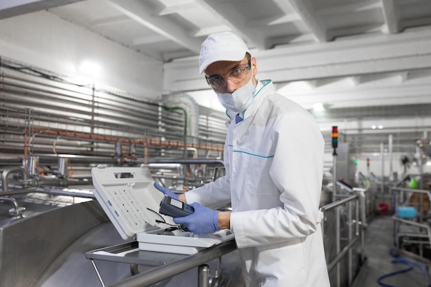 Technologist make set up of the special device while standing at the department of dairy factory