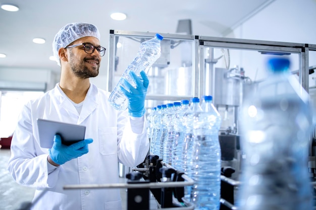 Technologist working in bottling factory doing quality control of drinking water before distribution