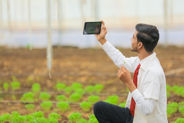 写真 技術と人々の概念、若いインドの農学者は温室でタブレットやスマートフォンで自分撮りを取ります