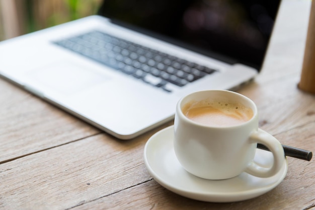 technology, business and modern life concept- close up of open laptop computer and coffee cup on table at office or hotel room