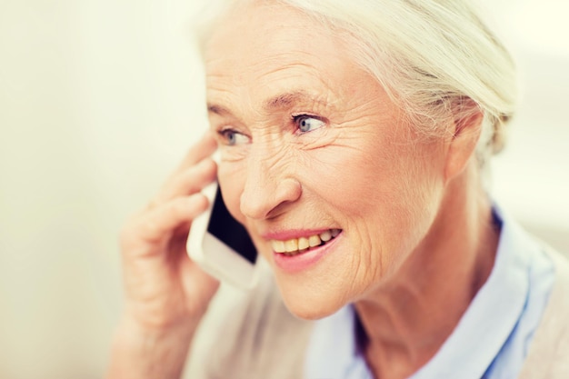 technology, communication age and people concept - happy senior woman with smartphone calling at home