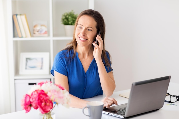 technology, communication and people concept - happy woman calling on smartphone at office or home