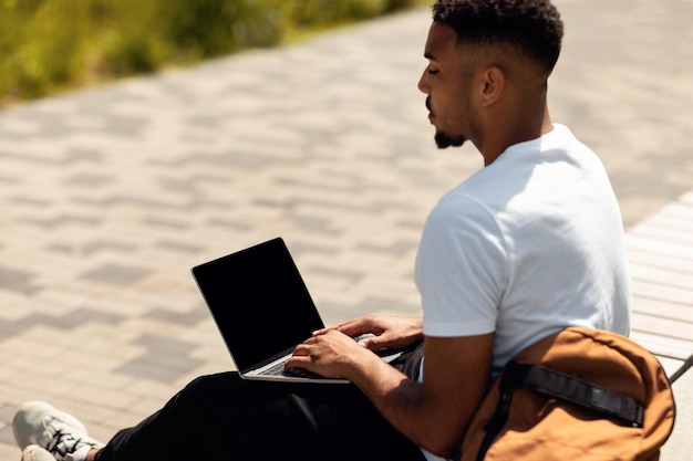 야외에서 검은색 빈 화면이 있는 현대적인 PC 컴퓨터를 사용하는 기술 개념 아프리카계 미국인 남자