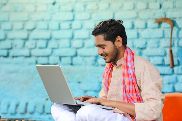 Concetto di tecnologia: agricoltore indiano che utilizza laptop a casa