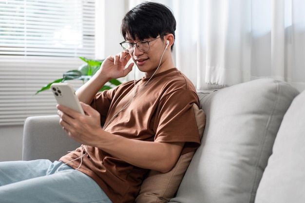 Technology concept the person who wears glasses and headphones\
sitting on the grey couch