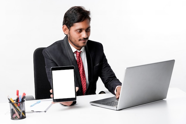 Концепция технологии: молодой индийский бизнесмен, показывая экран планшета в офисе