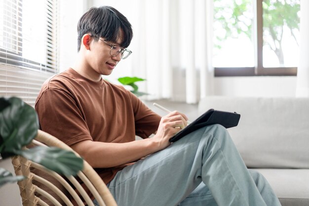 技術コンセプトiPadを持って椅子に座っている若い男