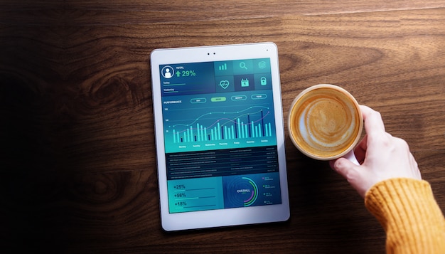 Tecnologia, finanza e marketing aziendale nel concetto di vita quotidiana. la donna mostra i grafici e i grafici di coffee coffee su tablet digitale. vista dall'alto