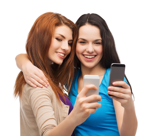 technology, friendship and people concept - two smiling teenagers with smartphones