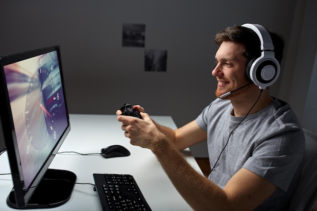 technology, gaming, entertainment, let&amp;#39;s play and people concept - happy young man in headset with controller gamepad playing computer game at home and streaming playthrough or walkthrough vid