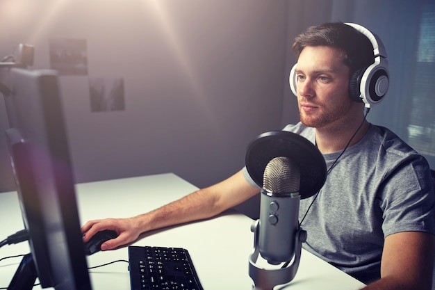 technology gaming entertainment lets play and people concept young man in headset with pc computer playing game at home and streaming playthrough or walkthrough video