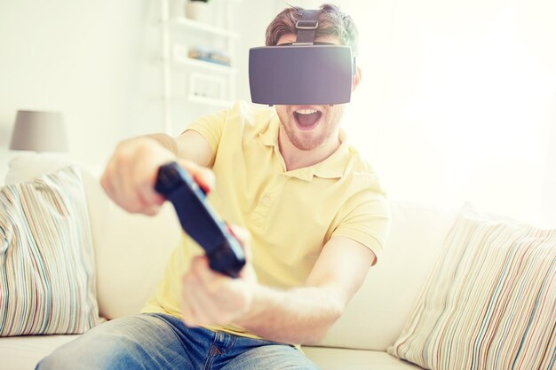 Foto tecnologia giochi intrattenimento e persone concetto giovane felice con cuffie di realtà virtuale o occhiali 3d con controller gamepad giocare a videogiochi di corsa a casa