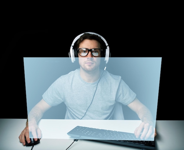 기술, 게임, 플레이하자 및 사람 개념 - PC 컴퓨터가 게임을 하고 스트리밍 플레이스루 또는 가상 화면이 있는 워크스루 비디오를 사용하여 헤드셋과 안경을 쓴 청년 또는 해커