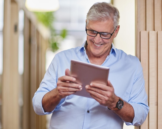 Technology has helped him achieve his goals Cropped shot of a handsome mature businessman using a table while standing in the hallway in his office