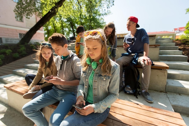 Photo technology, internet and people concept - group of teenage friends with smartphones outdoors