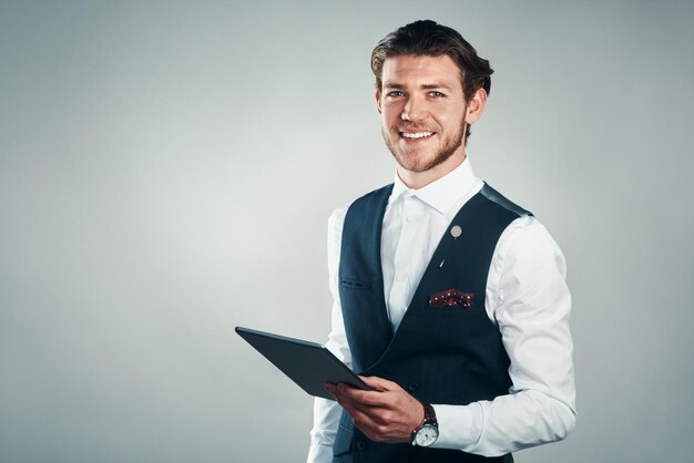 Technology is a big business asset Studio shot of a handsome young businessman using a tablet against a grey background