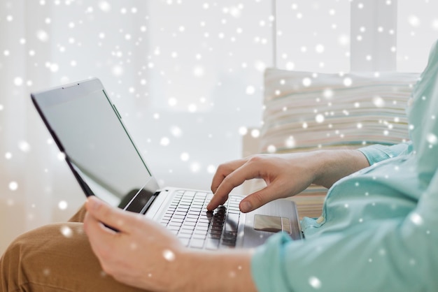 technology, leisure, advertisement and lifestyle concept - close up of man working with laptop computer and sitting on sofa at home