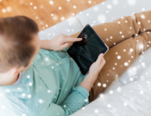 technology, leisure, lifestyle and advertisement concept - close up of man working with tablet pc computer sitting on sofa at home