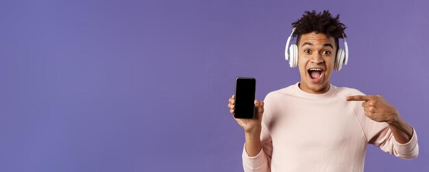 Technology and lifestyle concept portrait of excited impressed young man in headphones listening mus