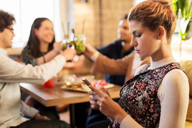 Foto tecnologia, stile di vita, vacanze e concetto di persone - donna con smartphone e amici al ristorante