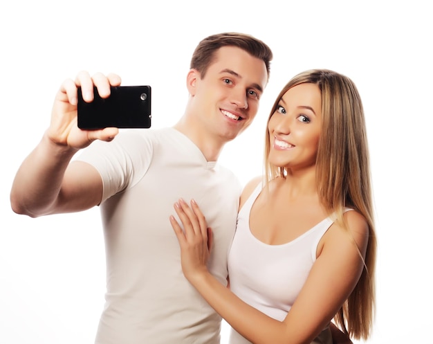 Technology love and friendship concept smiling couple with smartphone selfie and fun Studio shot over white background