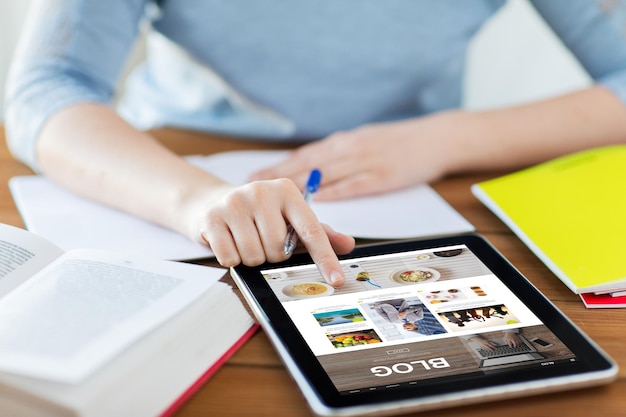 Foto concetto di tecnologia, media, internet e persone - primo piano della donna studentessa con la pagina web del blog sullo schermo del computer tablet pc e notebook a casa