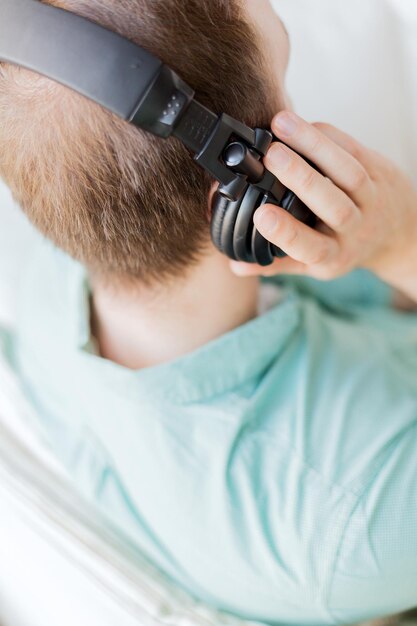 technology, music, leisure and happiness concept - close up of man in headphones at home from back