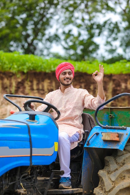 Technology and people concept, Portrait of young indian farmer with tractor