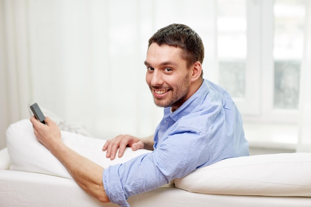 technology, people, lifestyle and communication concept - happy man with smartphone at home