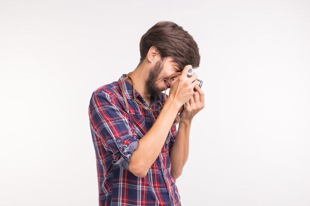 Concetto di tecnologia, fotografia e persone - bell'uomo in camicia a quadri che scatta una foto sulla fotocamera retrò.