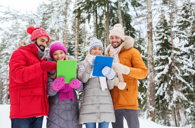 기술, 계절, 우정, 그리고 사람들의 개념 - 겨울 숲에서 태블릿 PC를 들고 웃고 있는 남녀 그룹