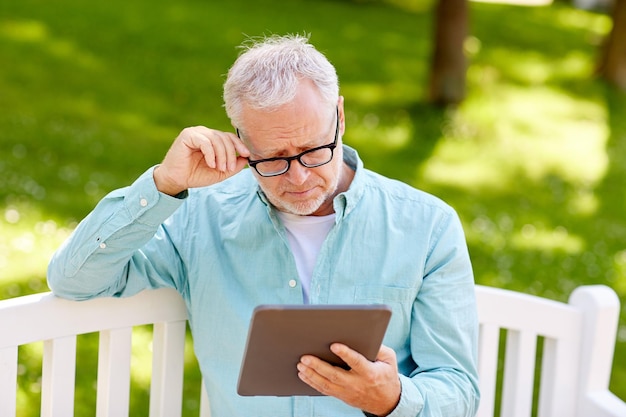 technology, senior people, and lifestyle, distance learning concept - old man with tablet pc computer at summer park