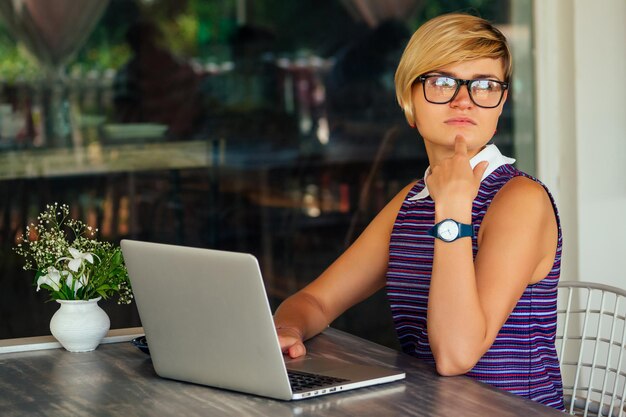 Technology and travel. Working outdoors. Freelance concept. Pretty young woman using laptop in cafe on tropical beach.Hooray victory success and successful deal concept promotion at work