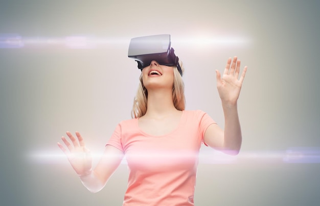 技術、仮想現実、エンターテイメント、人々 のコンセプト - 灰色の背景とレーザー光の上に仮想現実のヘッドセットまたは 3 d メガネを持つ幸せな若い女性