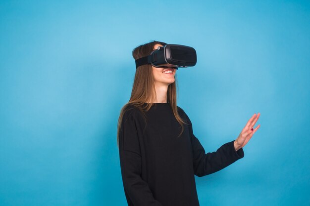 Technology, virtual reality, entertainment and people concept - happy young woman with virtual reality headset or 3d glasses.