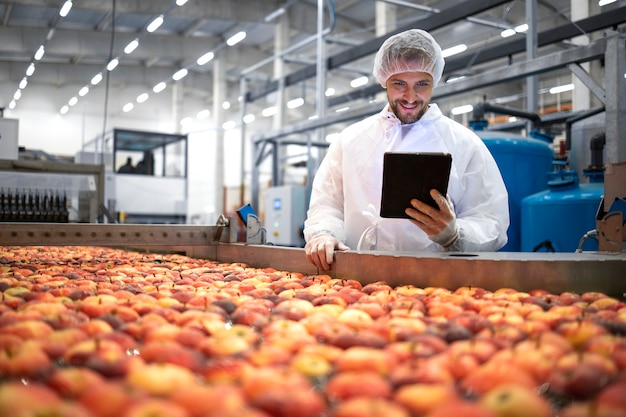 Technoloog die zich in de voedselverwerkende fabriek bevindt en de kwaliteit van appelfruit controleert.