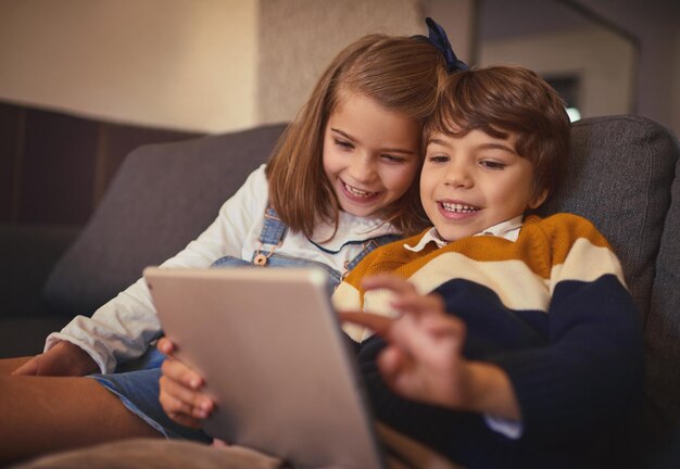 Techsavvy siblings Cropped shot of an adorable little boy and his older sister using a digital tablet while sitting on the sofa at home