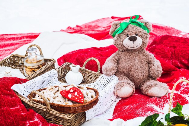 Teddy bear and a basket with bagels on a red bedspread