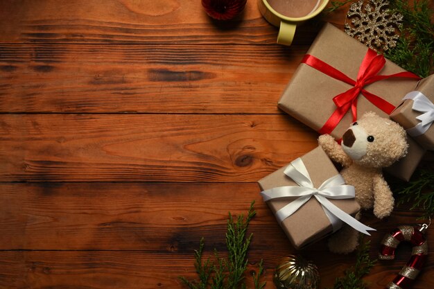 Teddy bear, Christmas gifts and cup of hot coffee on, fir tree branches on wooden table. Christmas and New year concept.