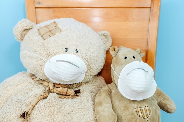 Teddy bear and hippo in a medical mask on a blue wall. Concept of 2019-20 coronavirus Covid-19 pandemic.