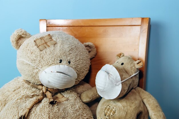 Teddy bear and hippo in a medical mask on a blue wall. Concept of 2019-20 coronavirus Covid-19 pandemic.