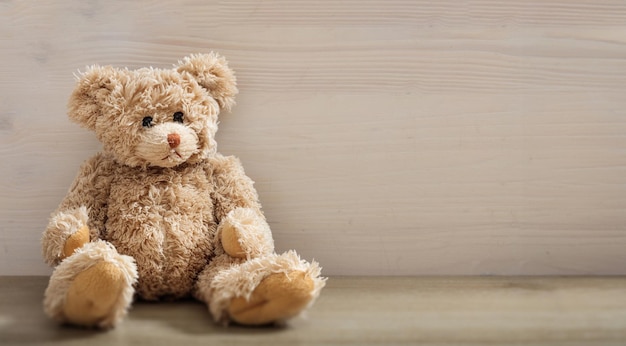 teddy bear is sitting on an empty wooden background brown lonely sad fluffy animal toy copy space