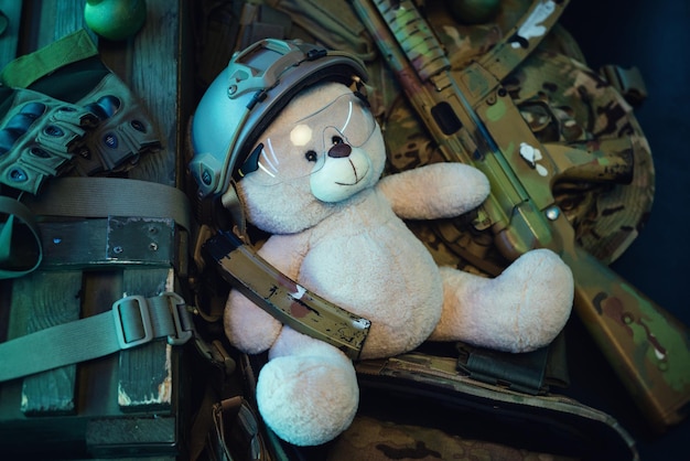 Photo a teddy bear in a military helmet among a pile of military ammunition a rifle grenades a bulletproof