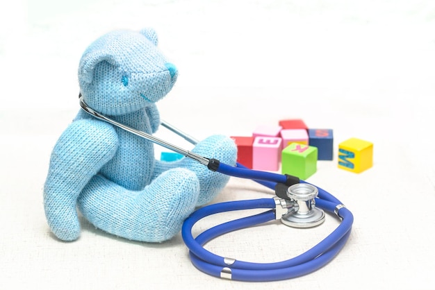 Photo teddy bear plush toys stethoscope and blocks on the floor meaning children's health medical care