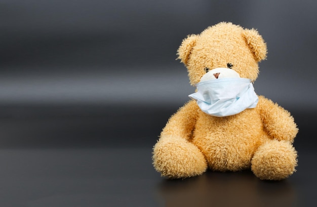 Teddy bear in a protective mask and eye glasses on a black background