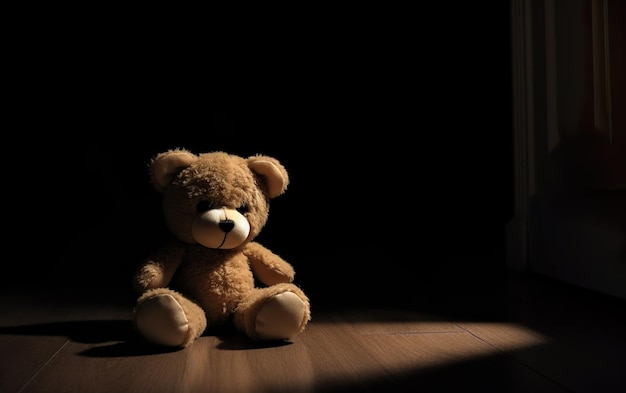 A teddy bear sits in a dark room with a black background.